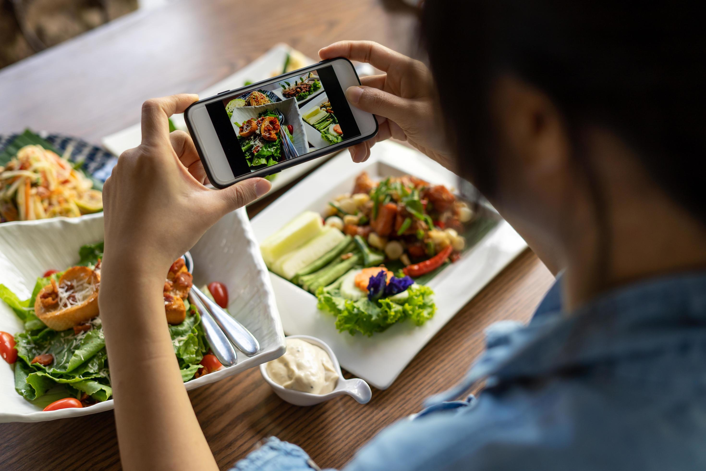 Woman take picture of a meal on the table after ordering food online to eat at home. Photography and use phone concepts Stock Free