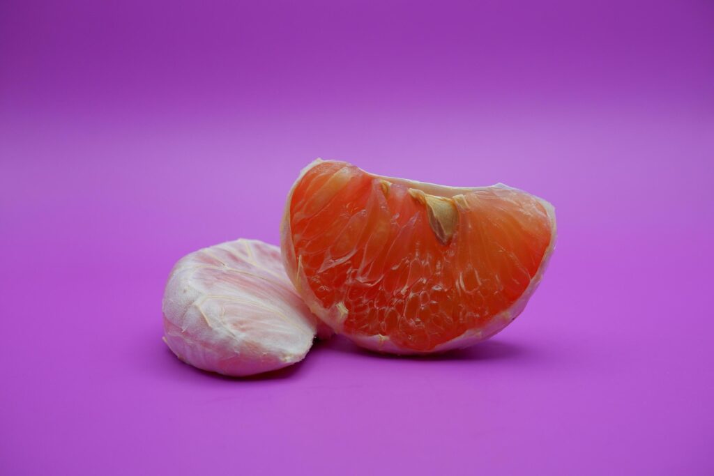 2 grapefruit isolated on purple background. 2 pieces of grapefruit that have been peeled until the grain of the orange is visible Stock Free