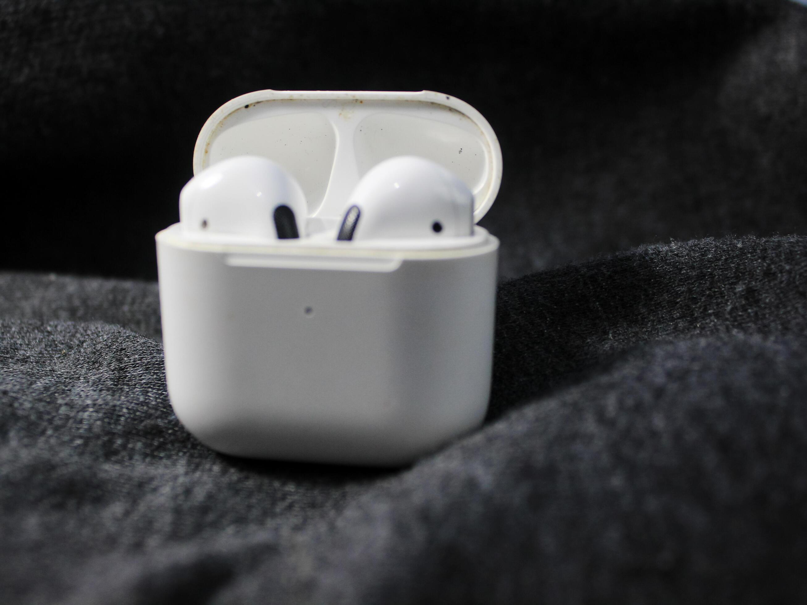 Closeup white TWS true wireless stereo earbuds in case isolated on black background. Stock Free