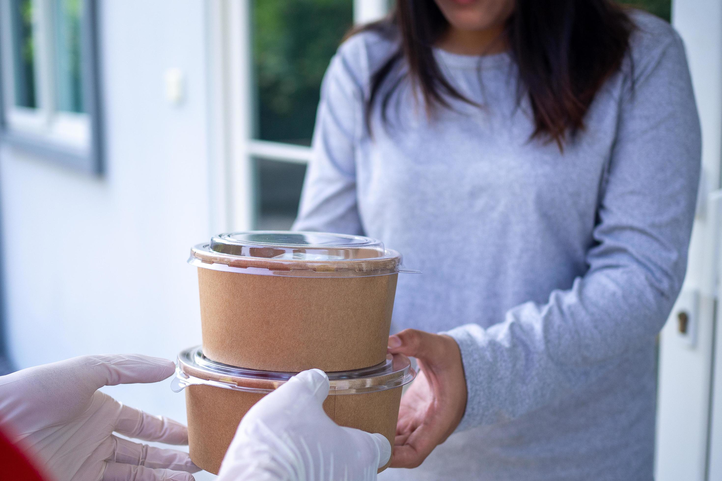 Delivery staff wear gloves for good hygiene, send food boxes to recipients in front of the house. Order food online and fast delivery. Stock Free