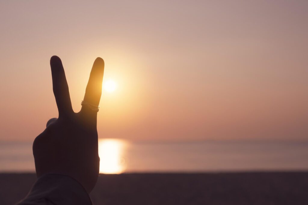 Peace out hand sign in front of a sunset Free Photo