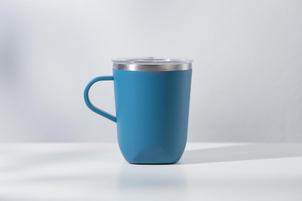 Blue tumbler made of stainless steel on a wooden table and white background Stock Free