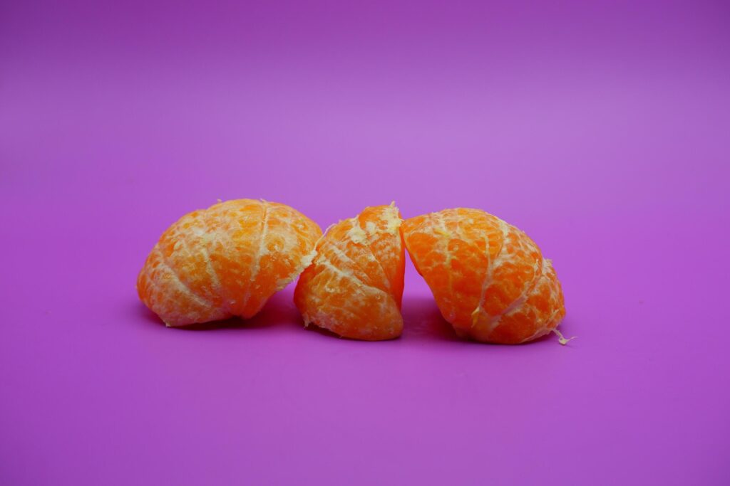 oranges that have been peeled and divided into several parts. orange isolated on purple background Stock Free