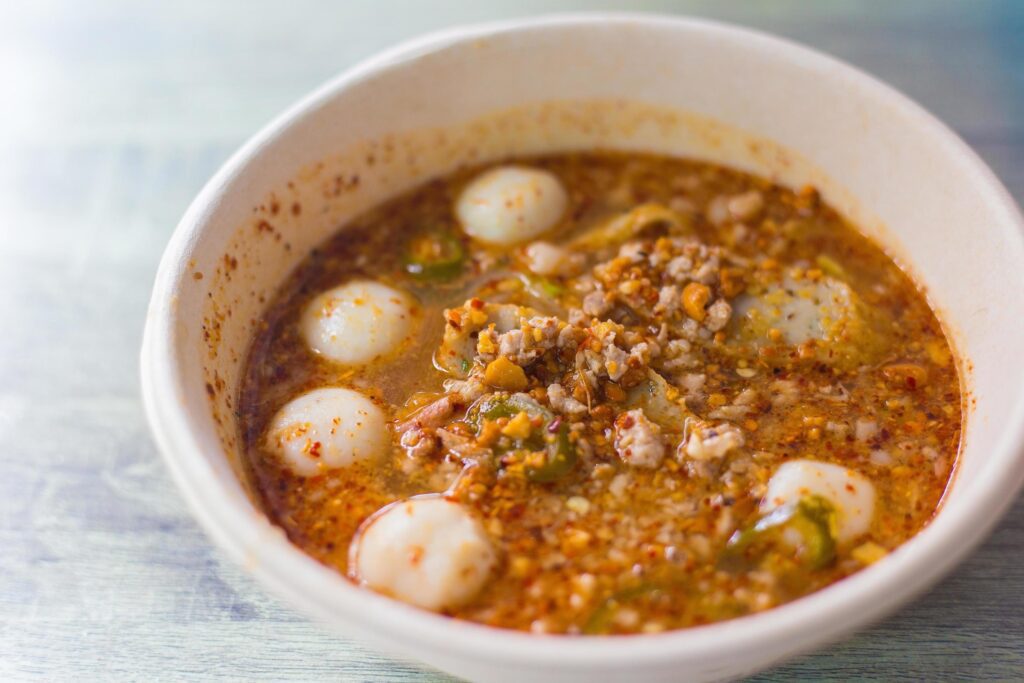 Closeup Spicy Tom Yum pork noodles with soup which contains fish balls, chilly pasted and lime juice. This noodles is a hot spicy and sour taste in Thai food style. Stock Free