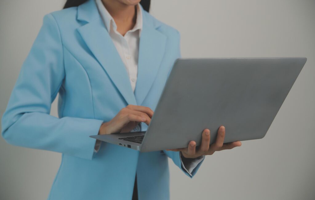 Portrait of a happy asian businesswoman working on laptop computer isolated over white background Stock Free