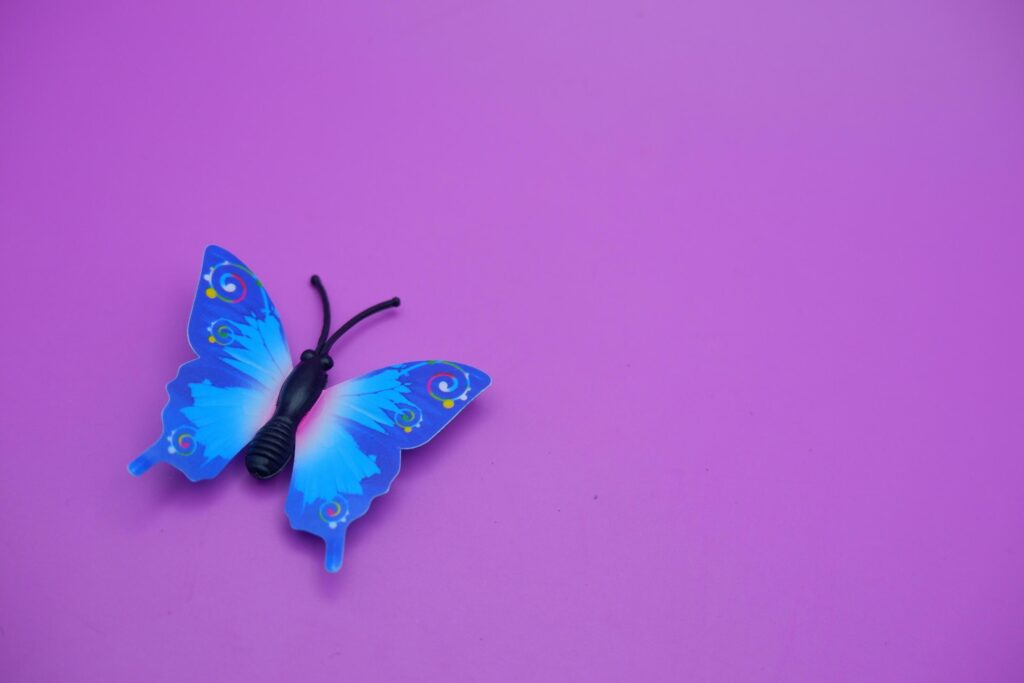 butterfly toy isolated on purple background. toy butterfly with blue wings. Stock Free