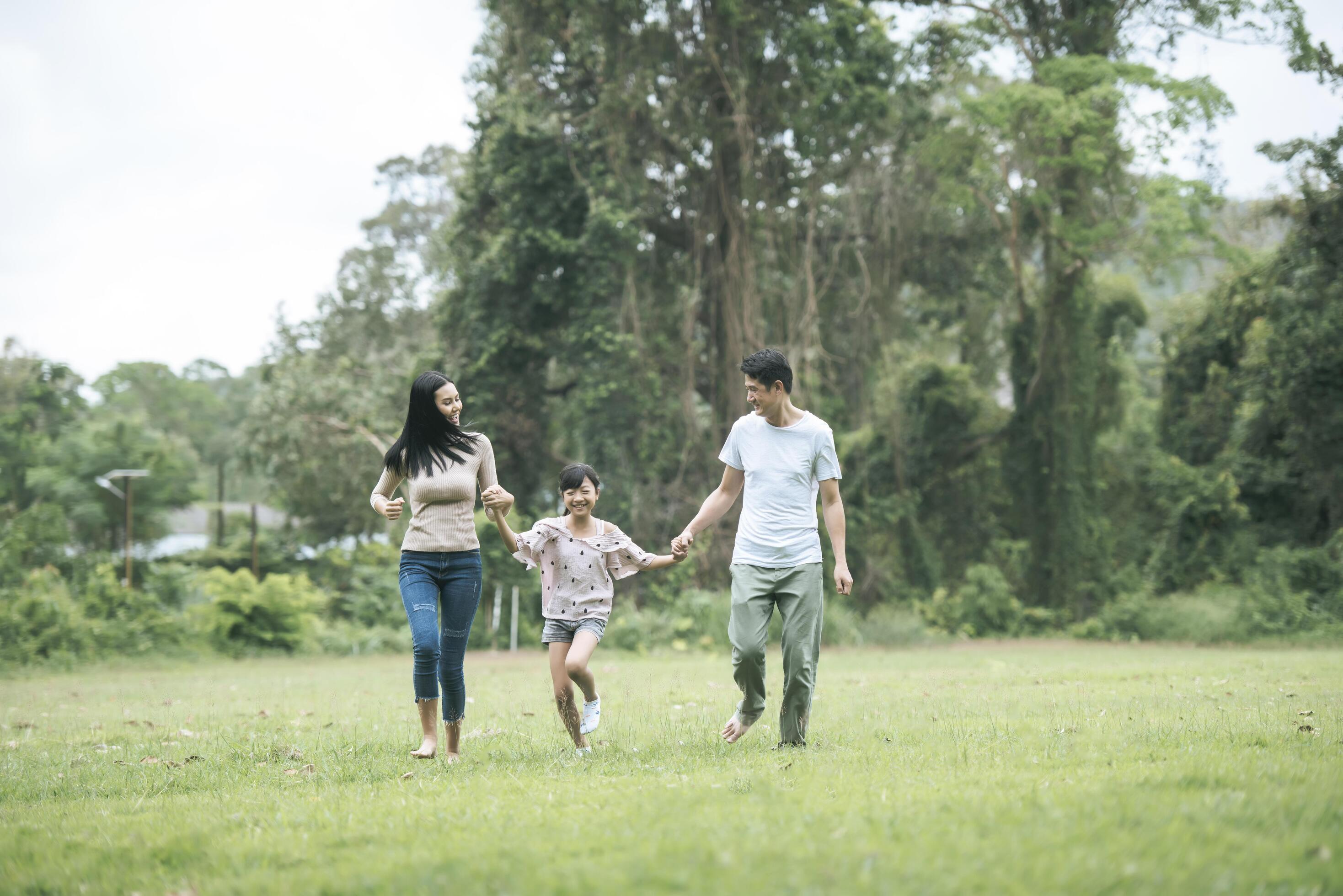 Happy parents and their daughter walking in the park, Happy family concept. Stock Free