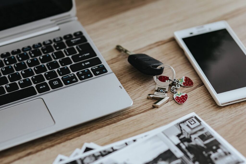 Black-and-white photos with a silver laptop, a smartphone, car keys, pencils and a camera Stock Free