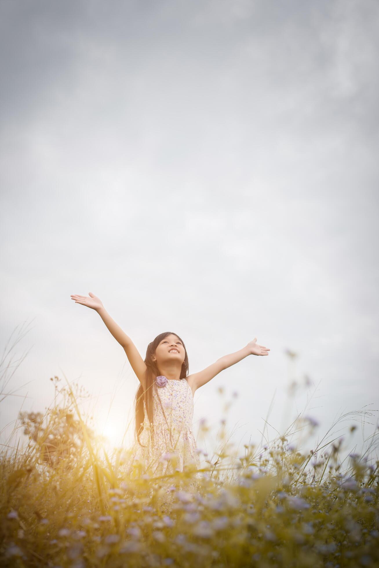 Little cute asian girl standing among the purple flower field sunshine day. Freedom enjoying with nature. Stock Free