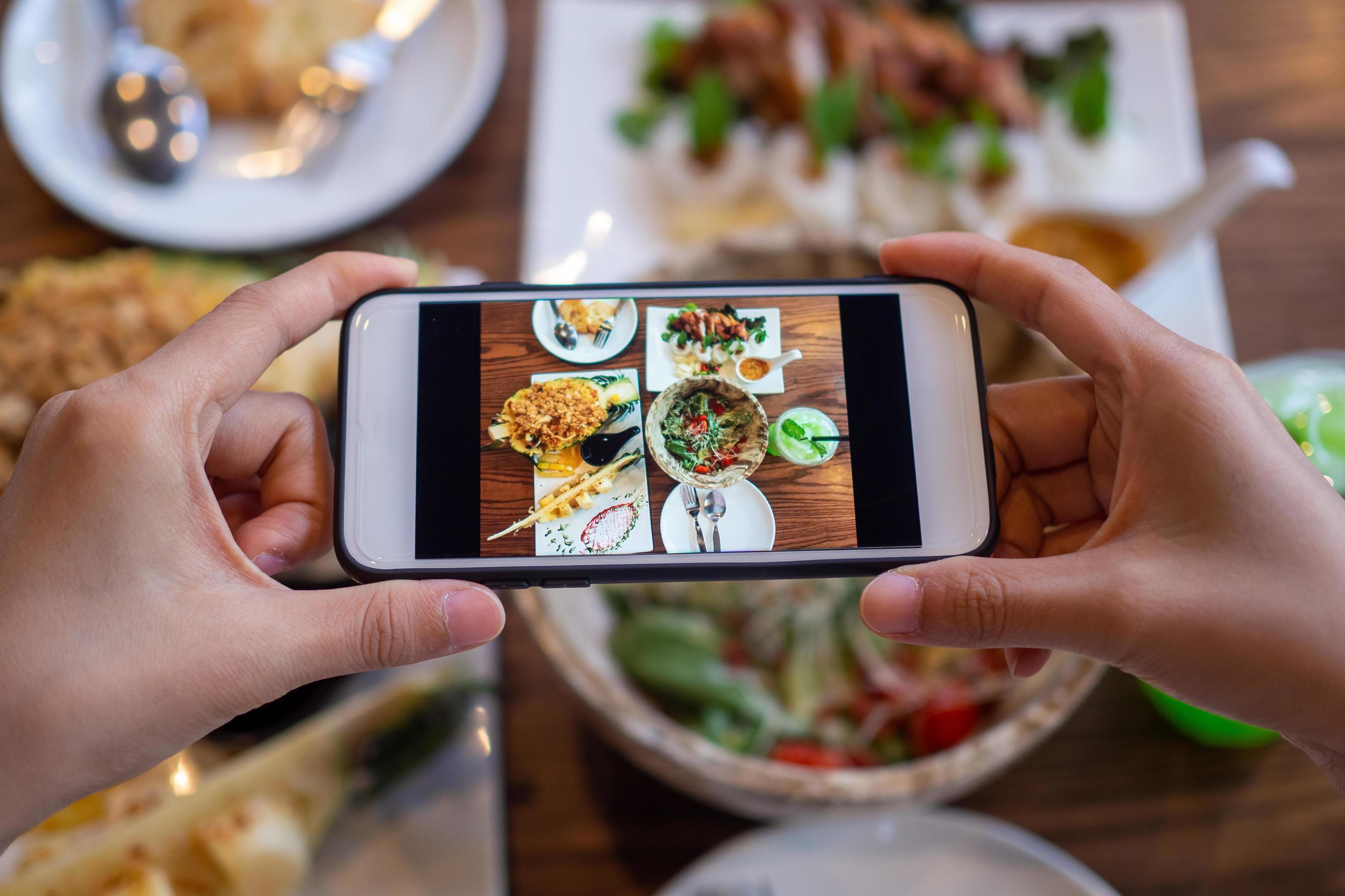 Take a photo of a smartphone for lunch or dinner. Woman taking picture with phone. Posting or sharing popular food for social media. Stock Free