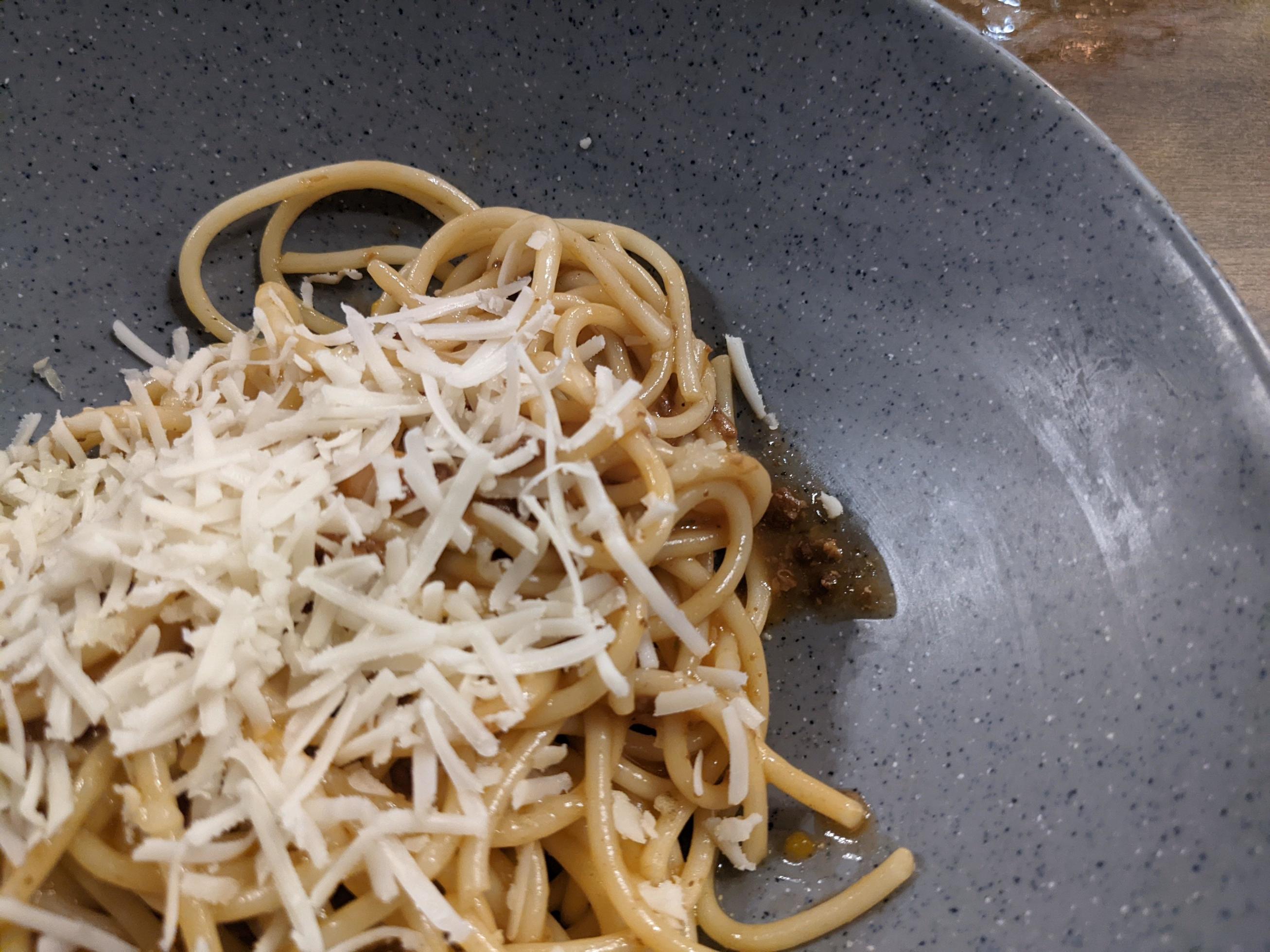 Spaghettis Bolognese with cheese cheddar topping on the grey bowl. The photo is suitable to use for food background, poster and food content. Stock Free