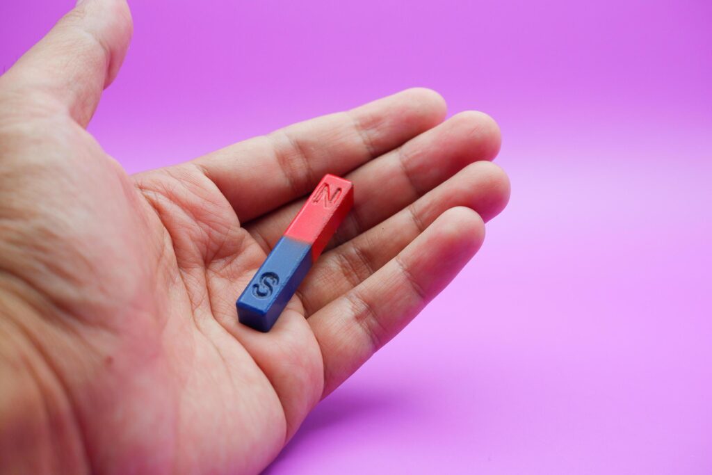 hand holding a bar magnet isolated on a purple background Stock Free