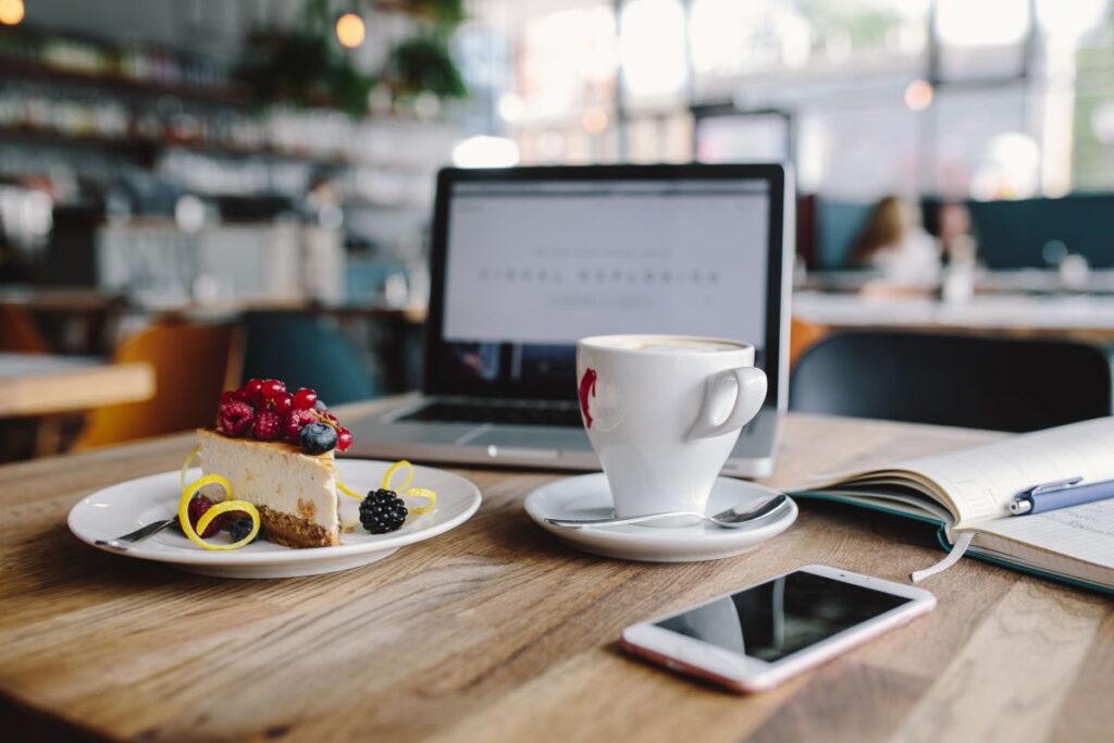 Working in a restaurant: Macbook, Cheese Cake and Cup of Coffee Stock Free