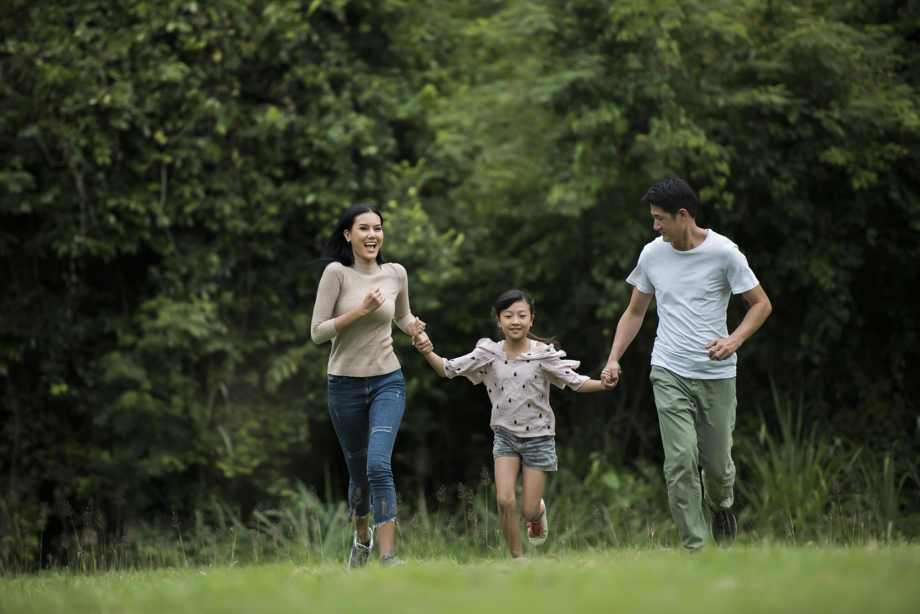 Happy family is having fun Mother, father and daughter are running in park. Stock Free