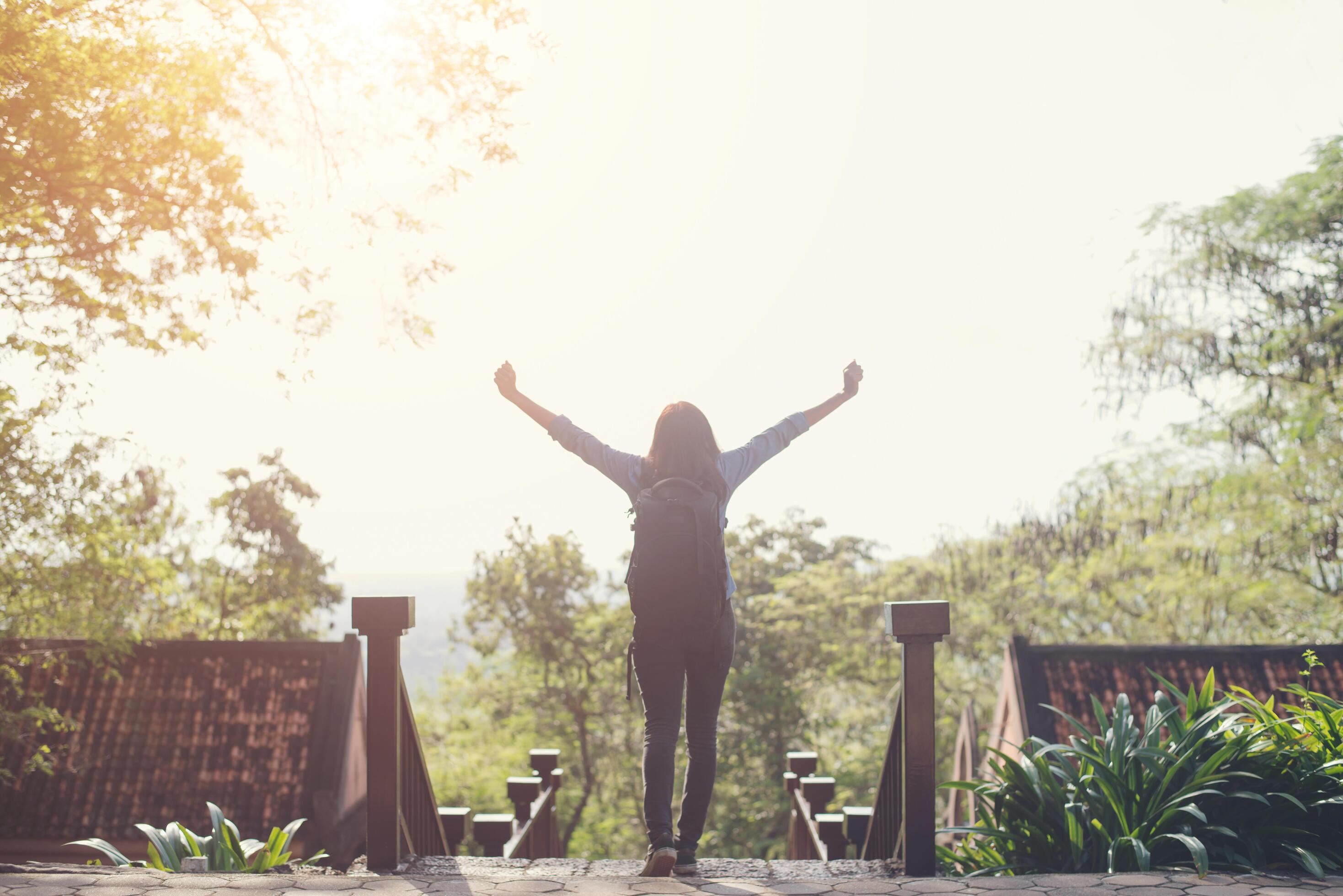 Freedom traveler hipster woman standing with raised arms and enjoying a beautiful nature. Achieved with adventure. Stock Free