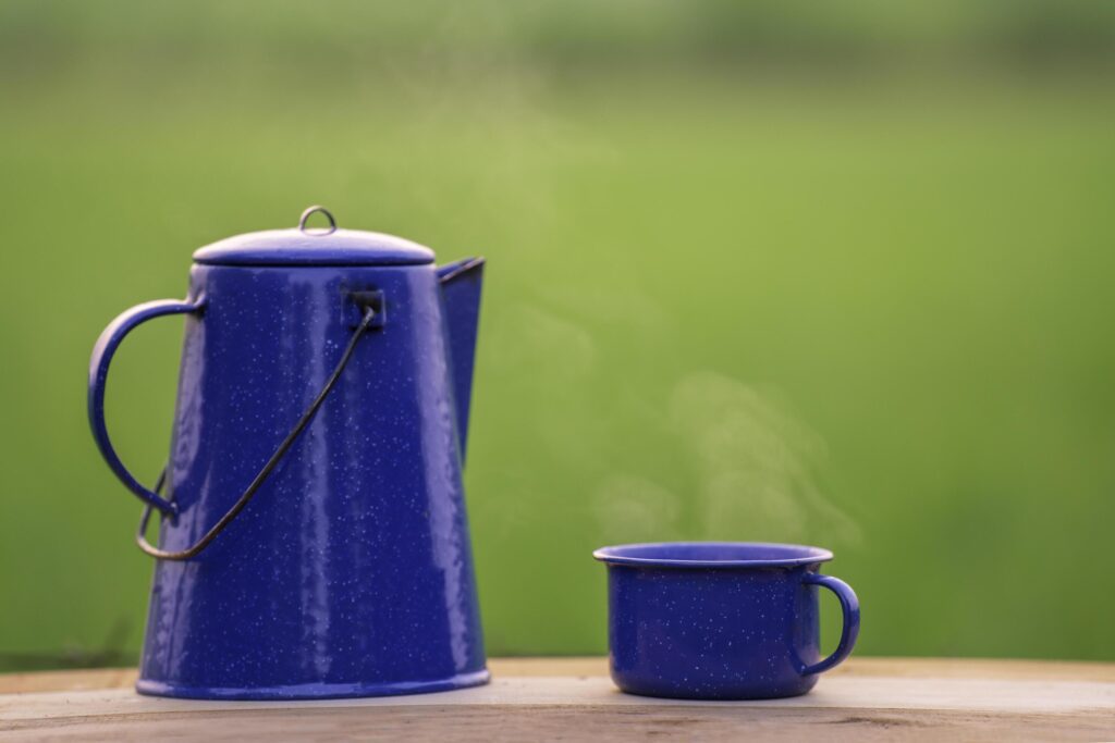 Kettle, blue enamel, and coffee mugs On an old wooden floor, Blurred background of rice fields at sunrise. Stock Free