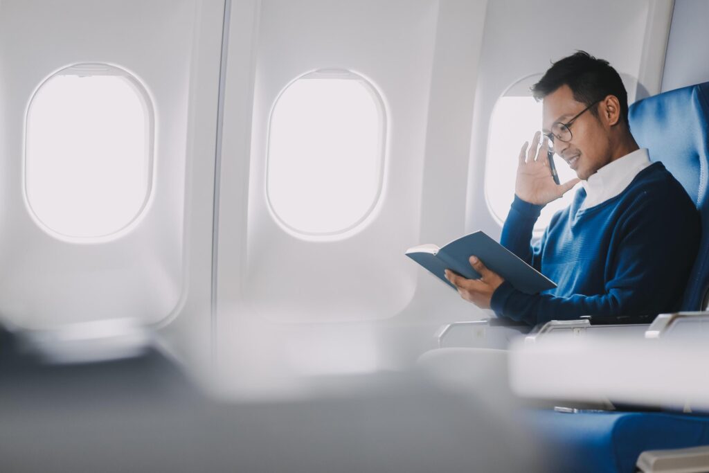 Handsome young Asian businessman or male executive manager reading a book during the flight for his business trip. Airplane or private jet concept Stock Free