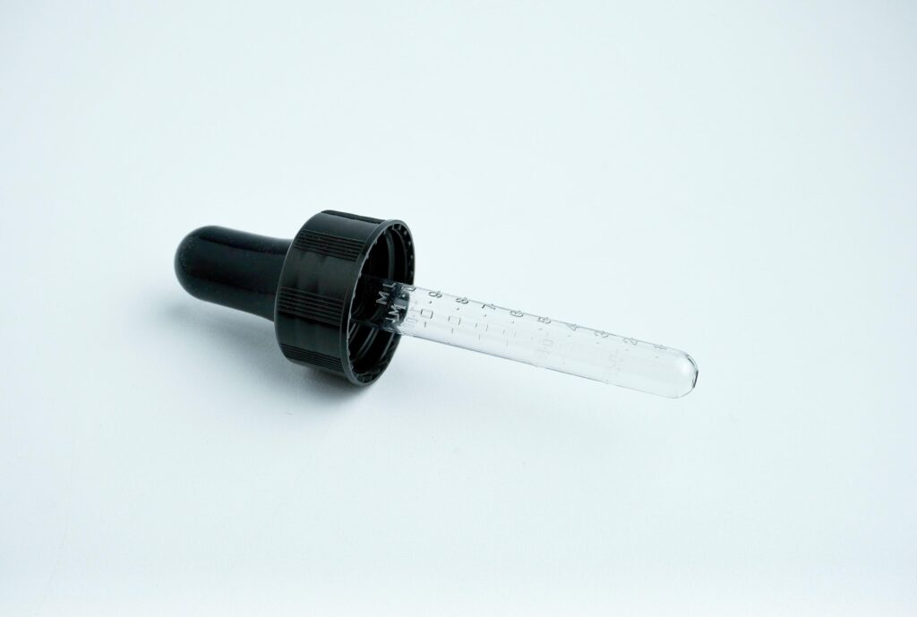 One single pipette lid pump with rubber and clear glass material. Small object photography isolated on horizontal ratio white background. Stock Free