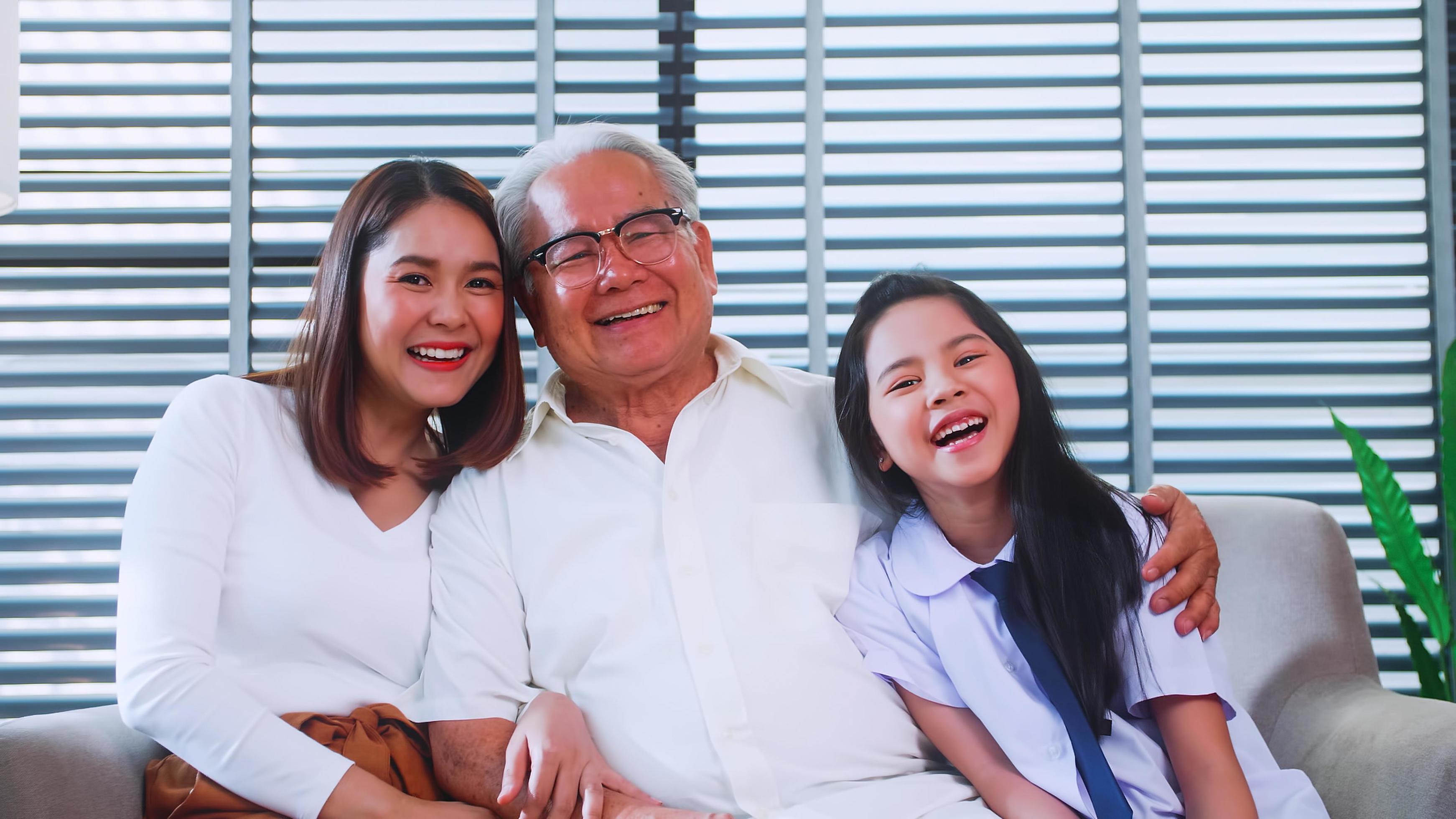 Happy family with grandfather, mother and little daughter spending time together in living room. Stock Free