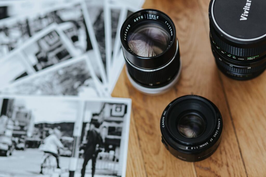 Old Zenit camera and a Canon camera with black-and-white photos on a wooden table Stock Free