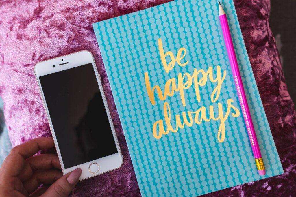 Blue notebook with a pink iPhone, headphones and a sweet bun Stock Free