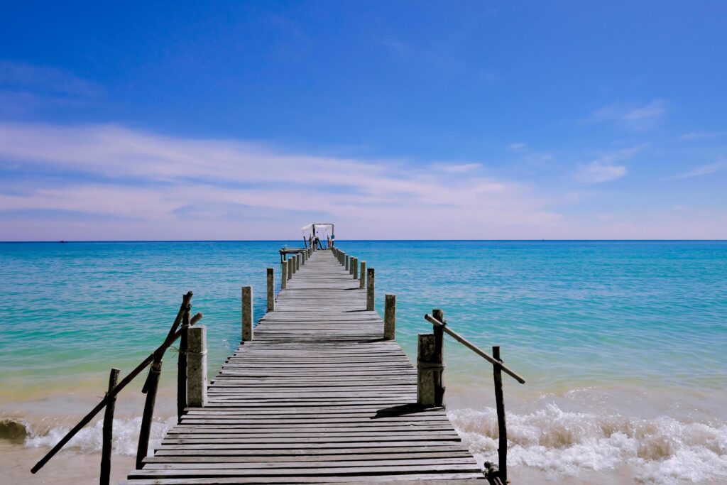 A wooden pier that stretches out to the sea,seascape view with cloudy and blue sky for travel in holiday relax time as summer Stock Free