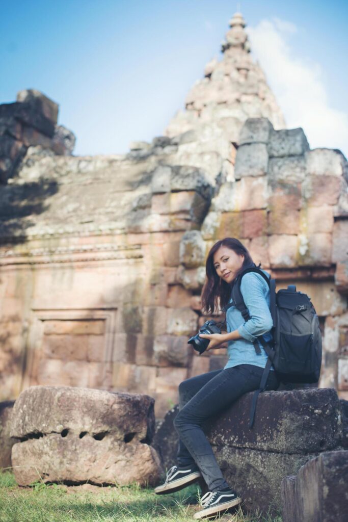 Young attractive woman photographer tourist with backpack coming to shoot photo at ancient phanom rung temple in thailand. Stock Free