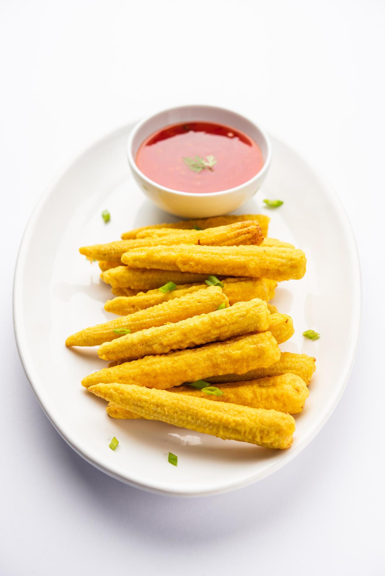 Crispy fried baby corn pakoda, pakora or Baby corn fritters served with ketchup, Indian food Stock Free