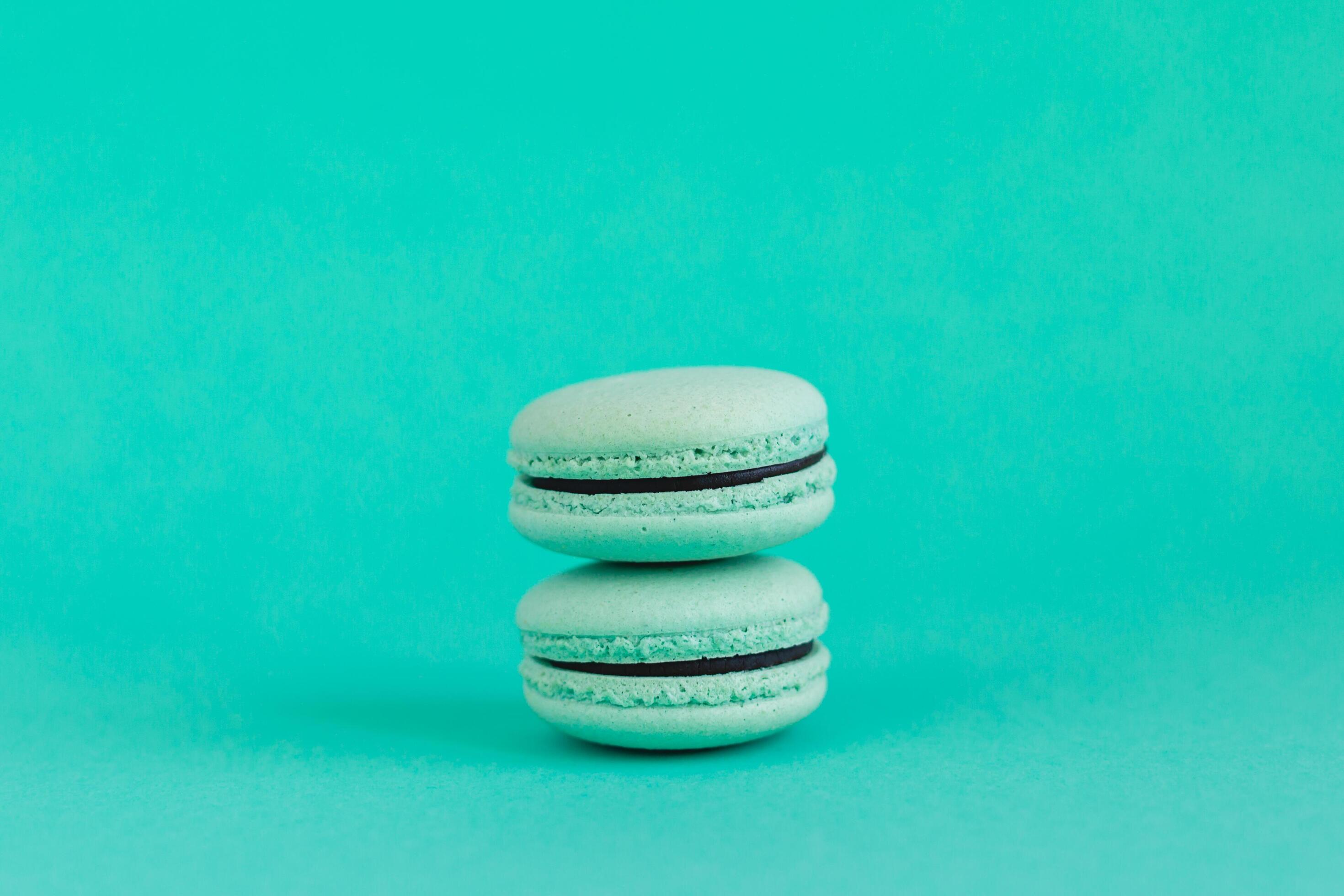 Two French macarons on a turquoise background. Mint macarons. Stock Free