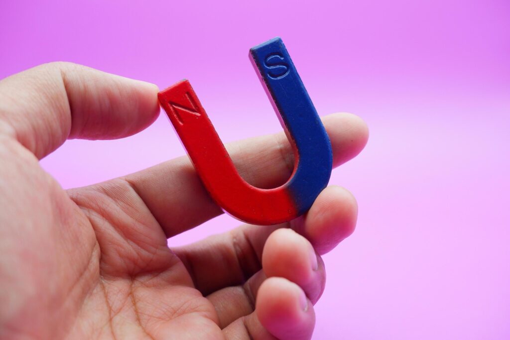 hand holding a horseshoe magnet isolated on a purple background Stock Free