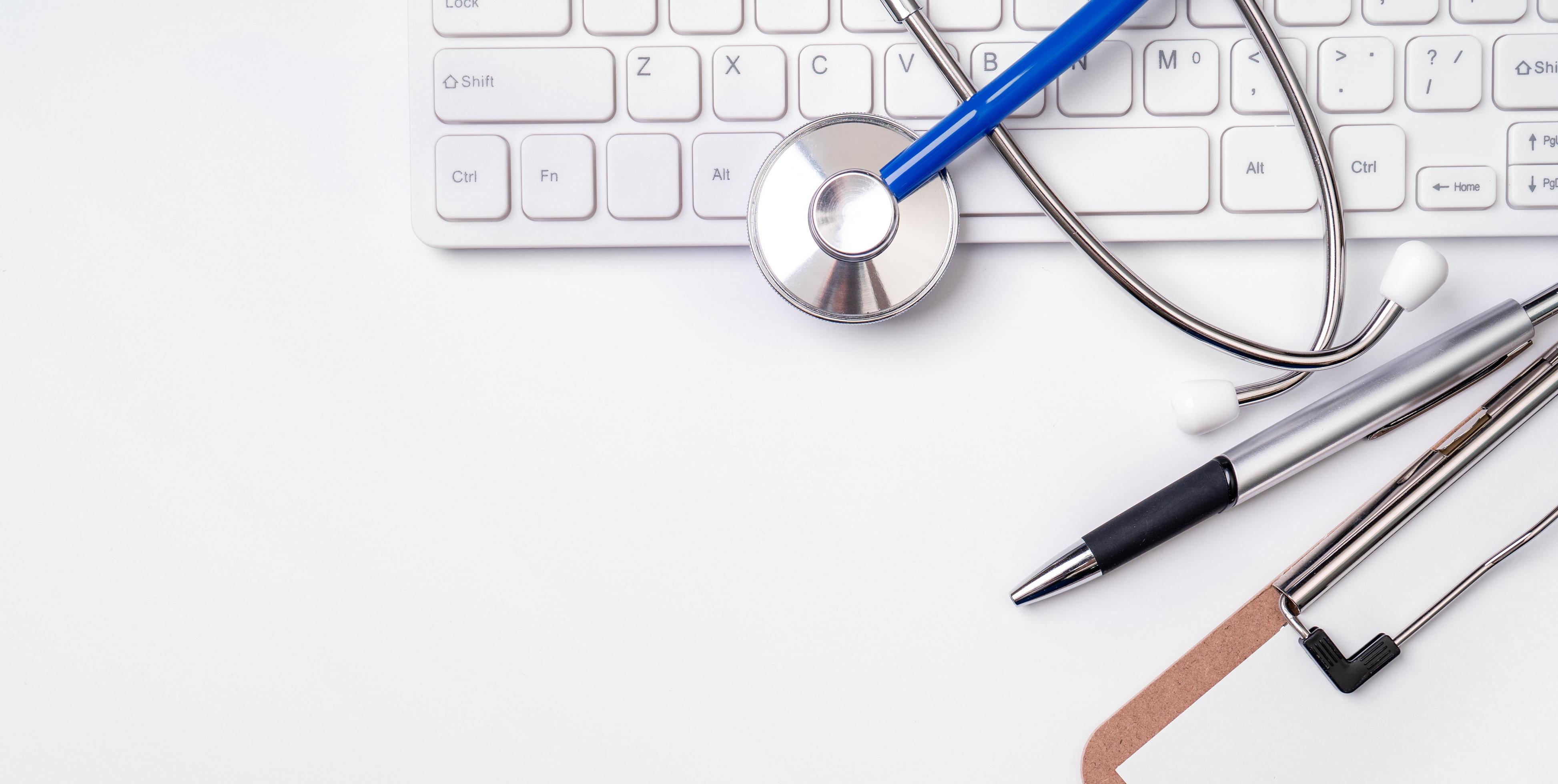 Stethoscope on computer keyboard on white background. Physician write medical case long term care treatment concept, top view, flat lay, copy space Stock Free