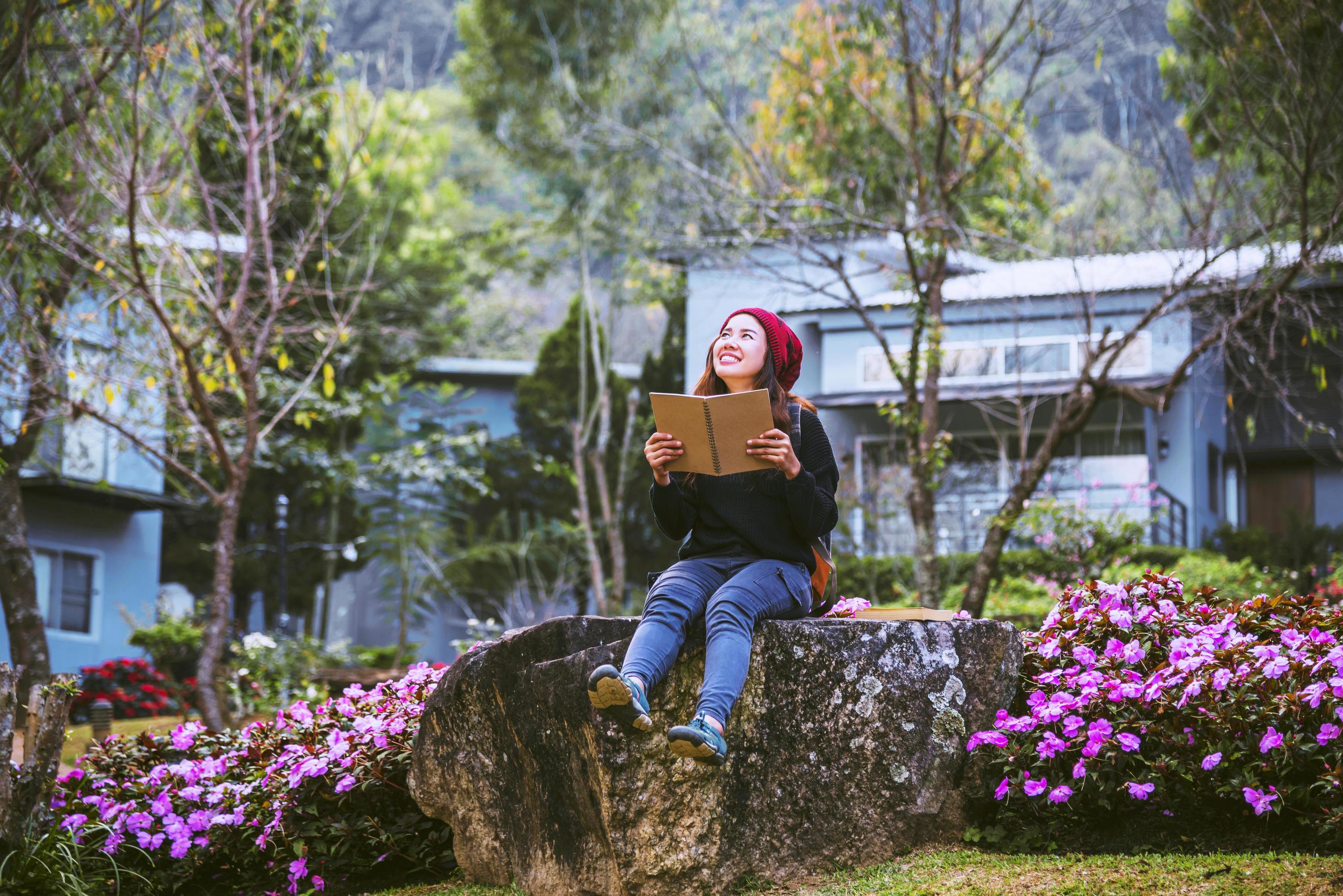 woman travel nature in the flower garden. relax sitting on rocks and reading books In the midst of nature at doi Inthanon. Stock Free