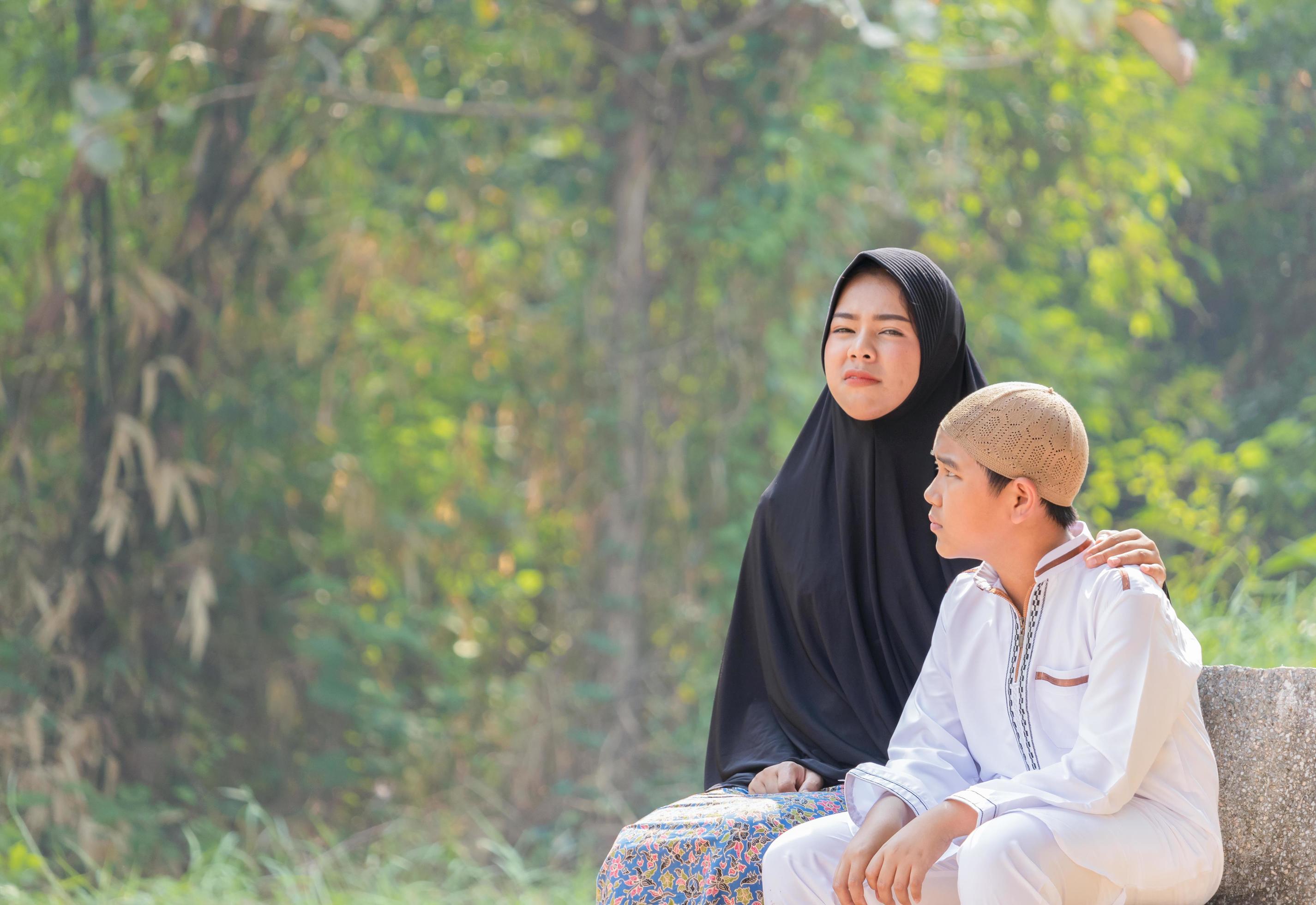 Muslim mother and son sit in the morning on a garden bench Stock Free