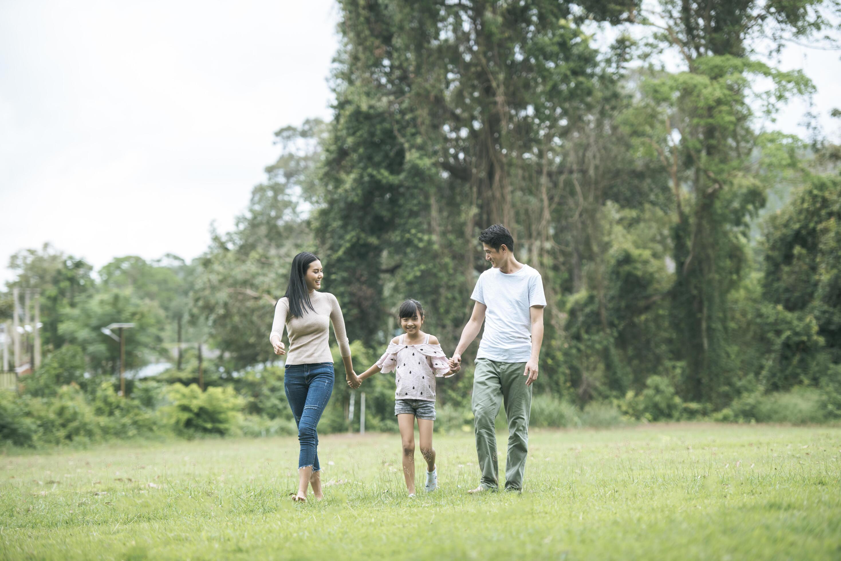 Happy parents and their daughter walking in the park, Happy family concept. Stock Free