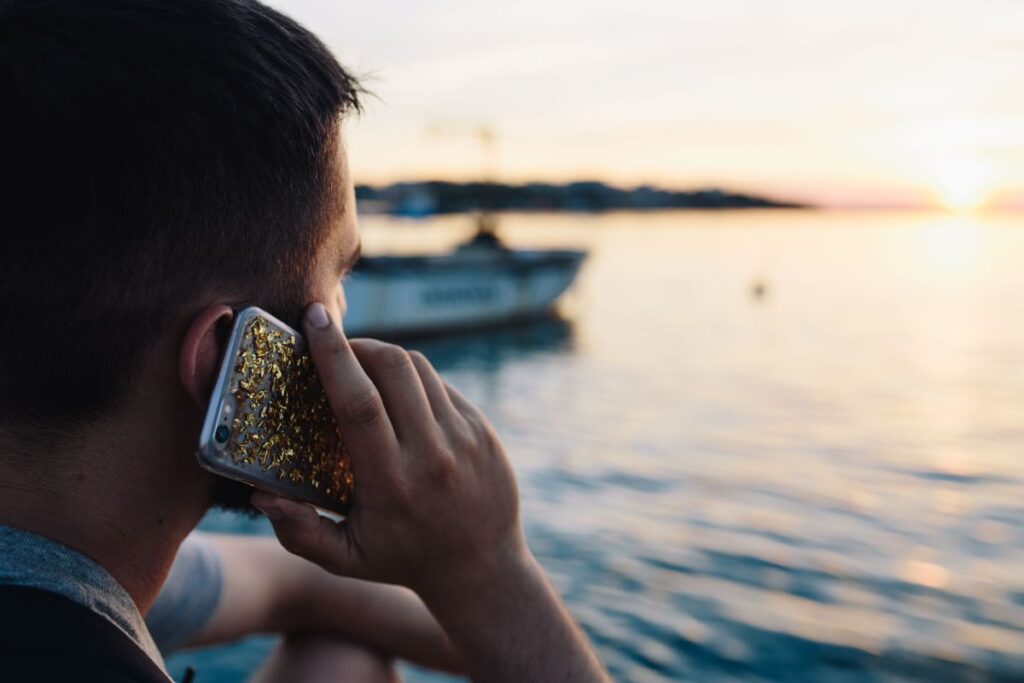 Mobile phone in man’s hands near the sea Stock Free