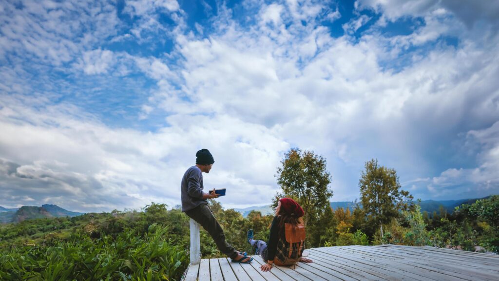 couple lover natural travel on the mountain, sitting relax reading books in the midst of nature on the white wooden bridge. Stock Free