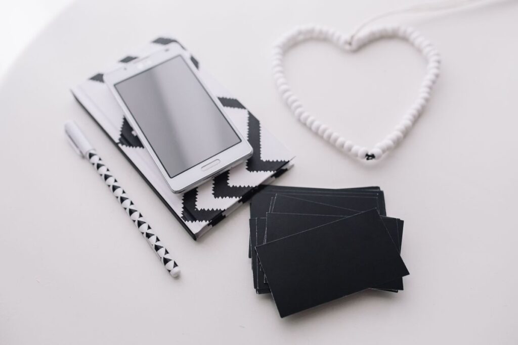 Black-and-white notebook and a white smartphone with various items Stock Free