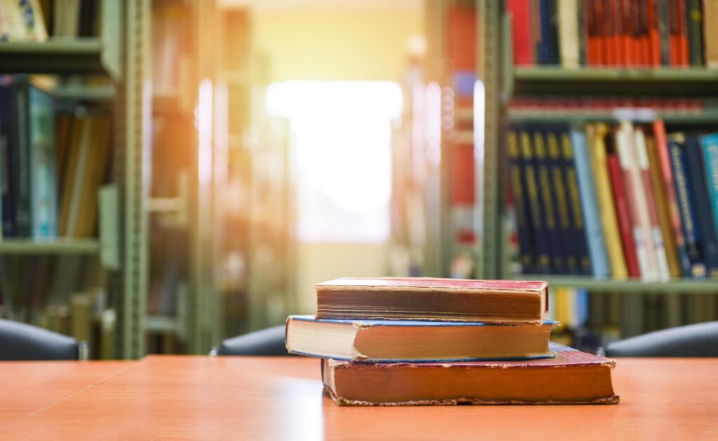 Old books on a wooden table – Book stack in the library room for business and education background , back to school concept Stock Free