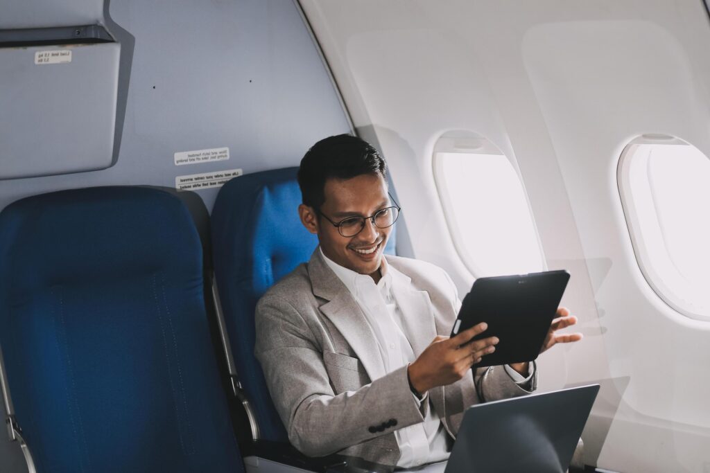 Airplane, travel and portrait of businessman working on laptop computer and smartphone while sitting in airplane. Stock Free