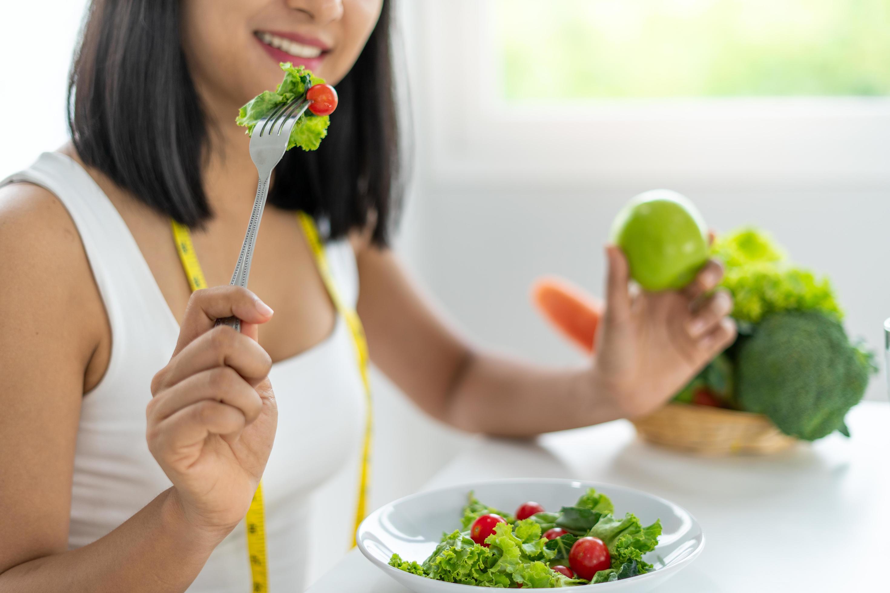 Beautiful Asian women are enjoying eating salad to lose weight. Healthy young woman eating vegetable salad. Dieting , Healthy food concepts. Stock Free