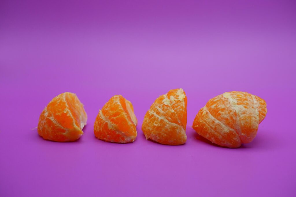 oranges that have been peeled and divided into several parts. orange isolated on purple background Stock Free