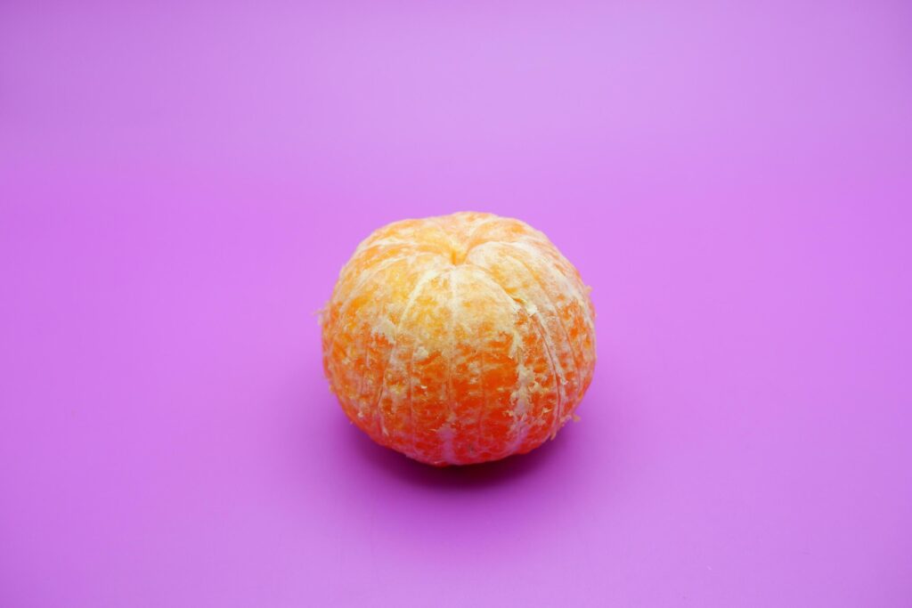 Peeled orange isolated on purple background Stock Free