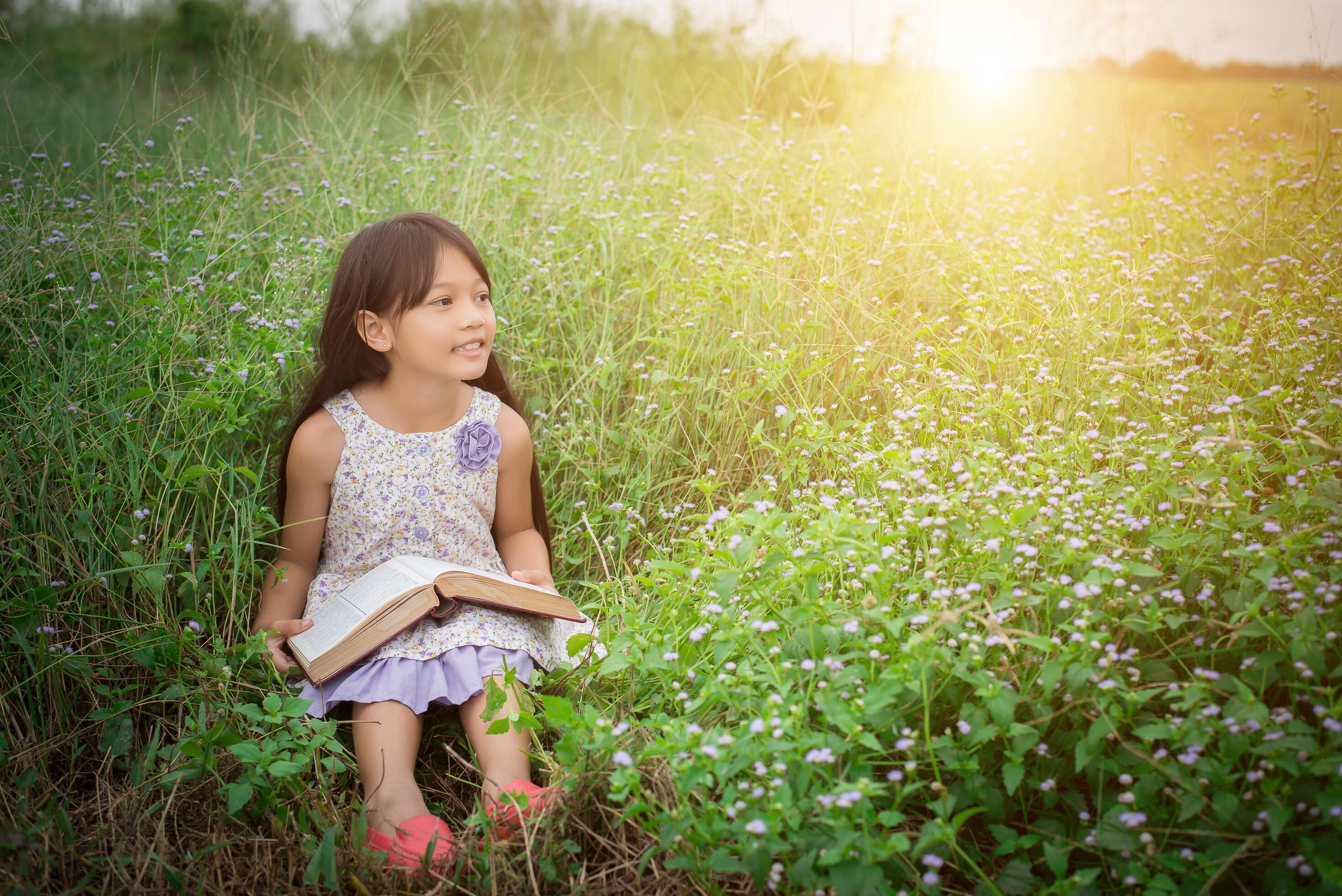 little cute asian girl reading book at nature. Stock Free