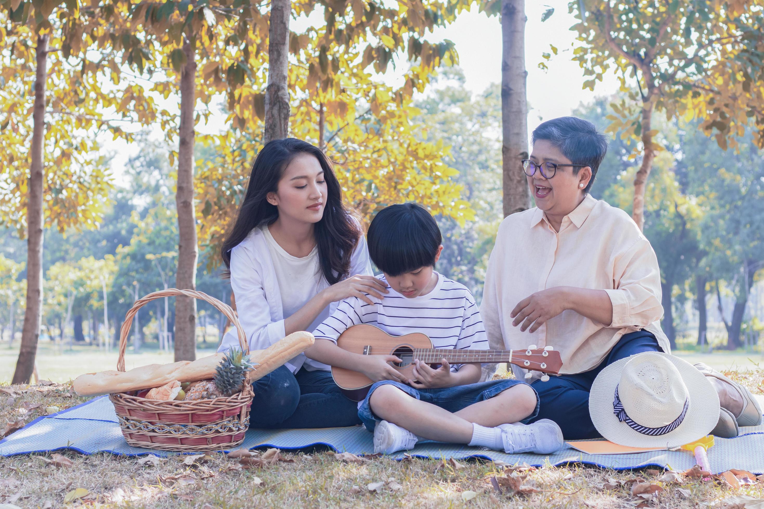 Asian family enjoys sitting in the park on the autumn holiday. Stock Free