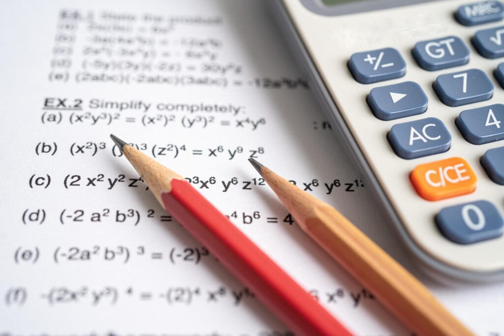 Pencil and calculator on mathematic formula exercise test paper in education school. Stock Free