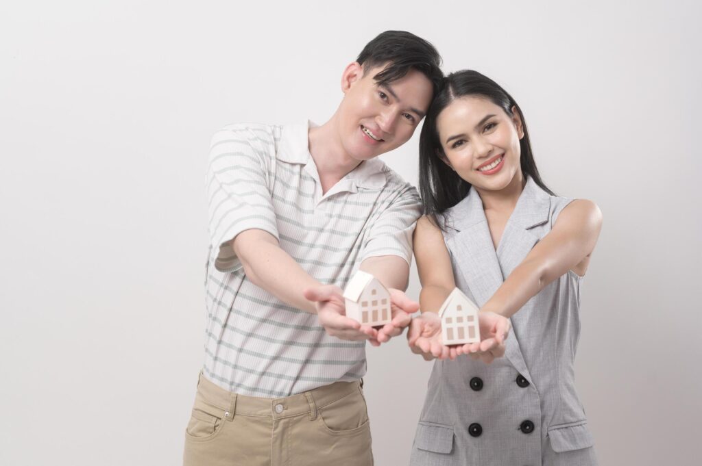 Happy couple of love holding small house over white background Stock Free