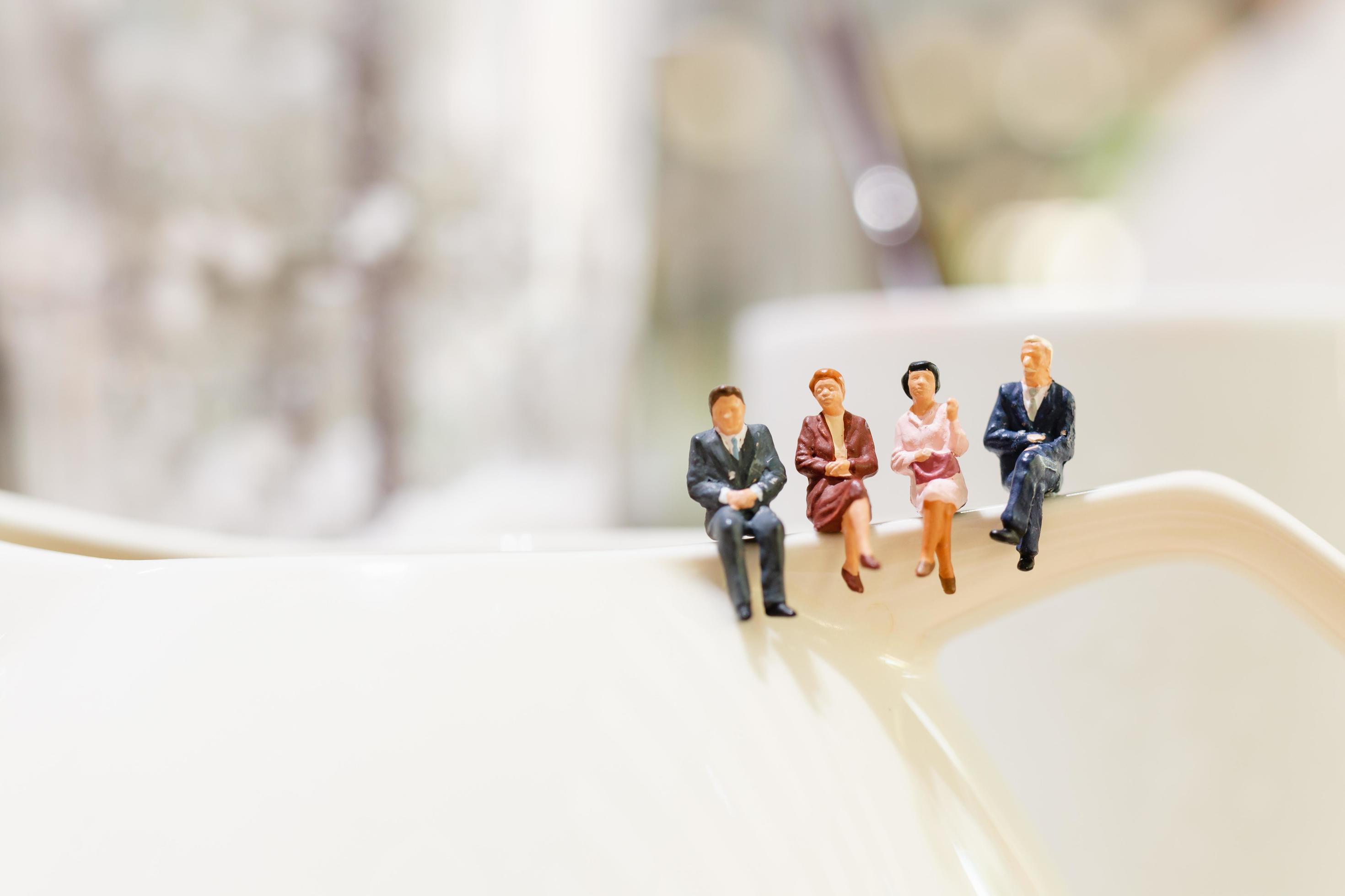 Miniature businesspeople sitting on a teacup Stock Free