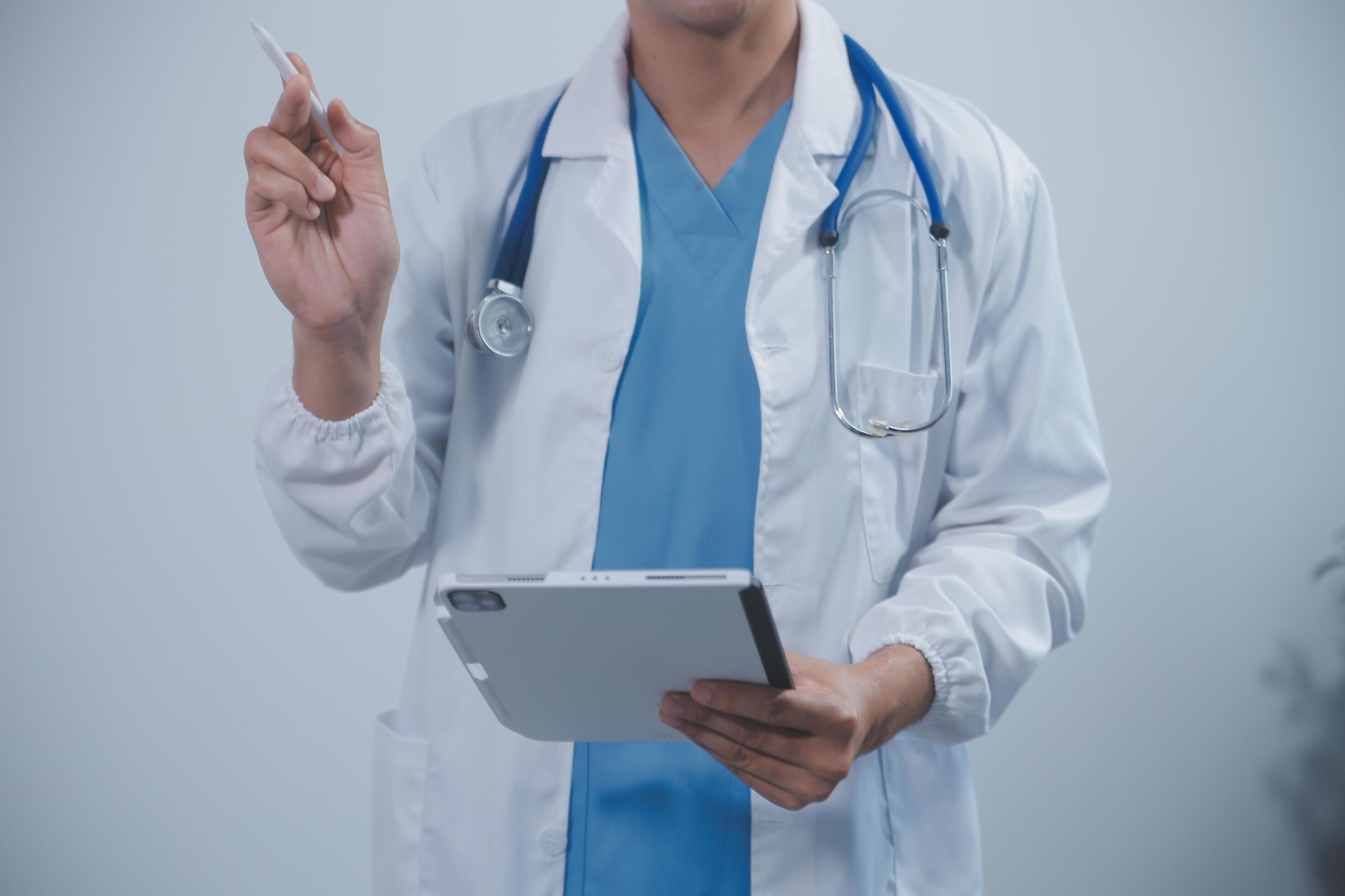 Mature male doctor with tablet pc is giving presentation. Blurred background indoors. Stock Free