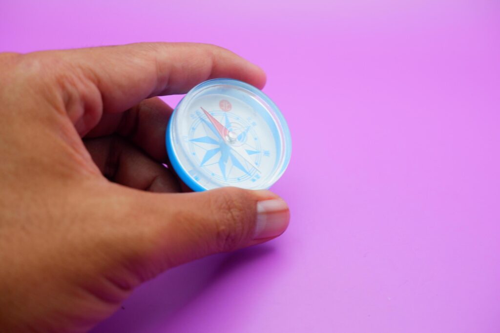 hand holding a compass isolated on a purple background Stock Free