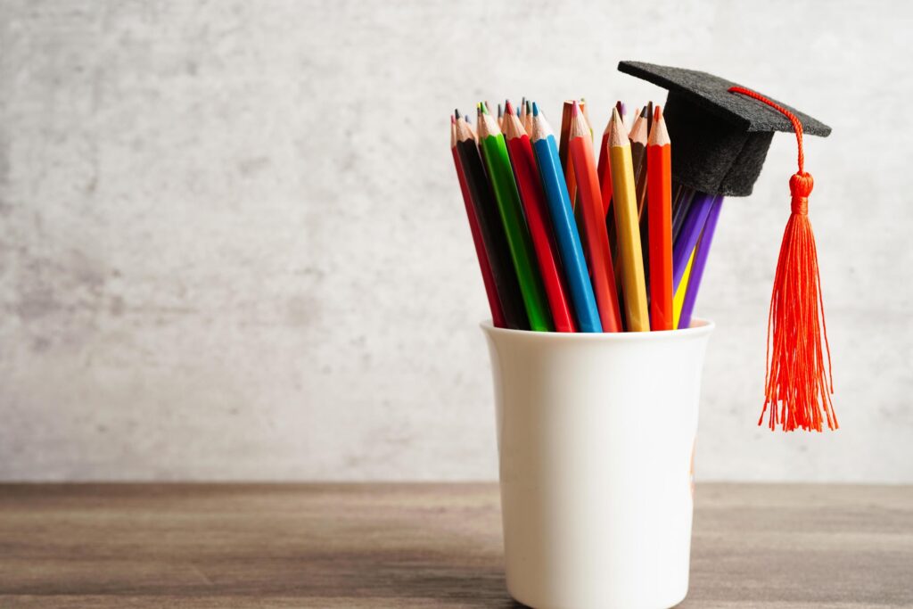 Graduation hat with colorful pencils on book with copy space, learning university education concept. Stock Free